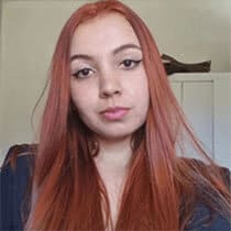 Uma mulher, com idade entre 20 e 25 anos, está olhando para a foto. Ela tem cabelo longo e ruivo